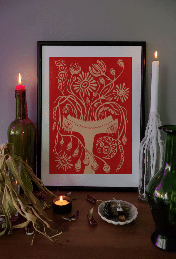 Red and orange folk botanical art print in black frame, styled with candles, dried herbs, and mystical decor for warm boho interiors.