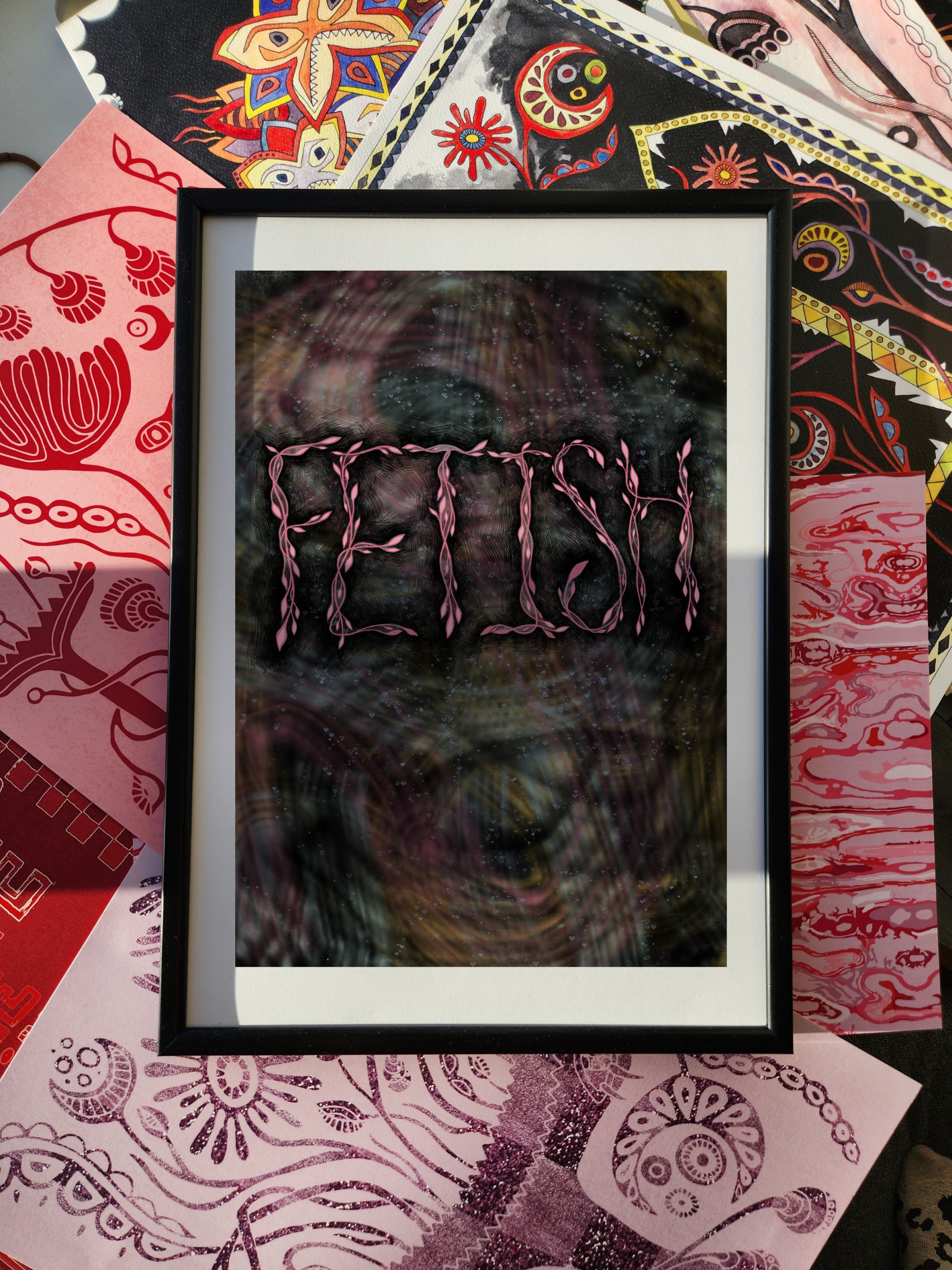 Edgy grunge wall art poster with bold typography print reading “FETISH,” framed and set against a colorful eclectic patterned fabric background.