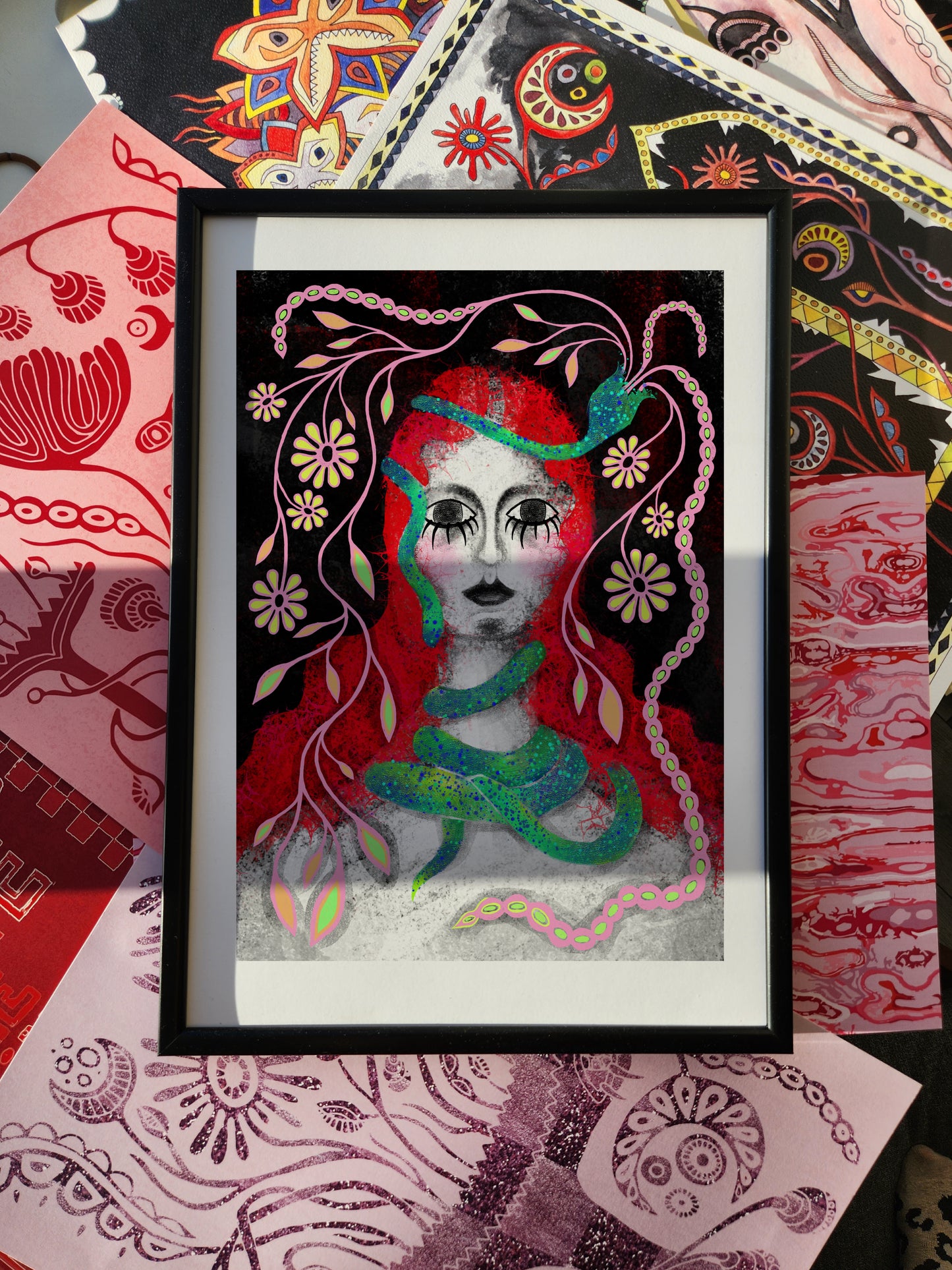 Female portrait poster featuring a surreal woman with red and green flowing hair, floral motifs, and expressive eyes, framed as modern wall art against a patterned eclectic fabric background.