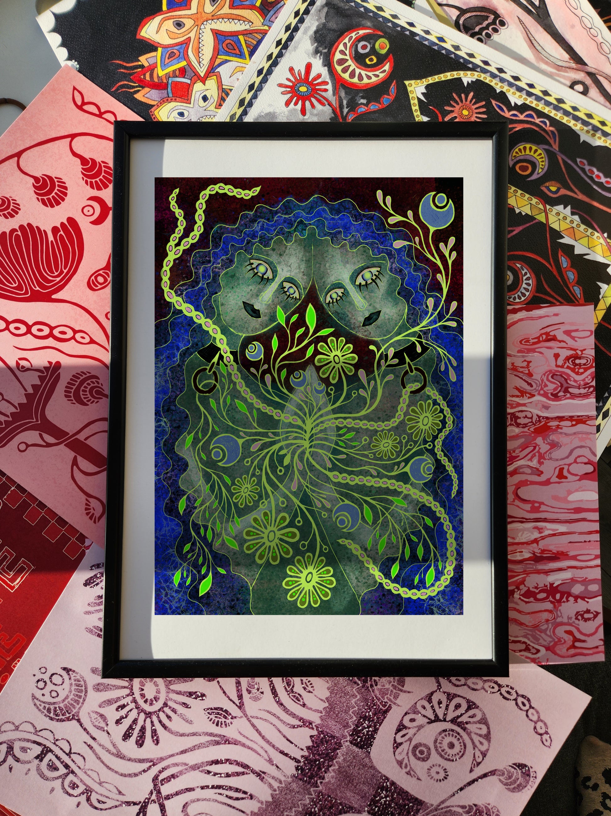 Sapphic wall art print featuring two female faces intertwined with surreal green floral patterns, moon symbol, and cosmic details, framed as a sapphic poster for modern interiors.